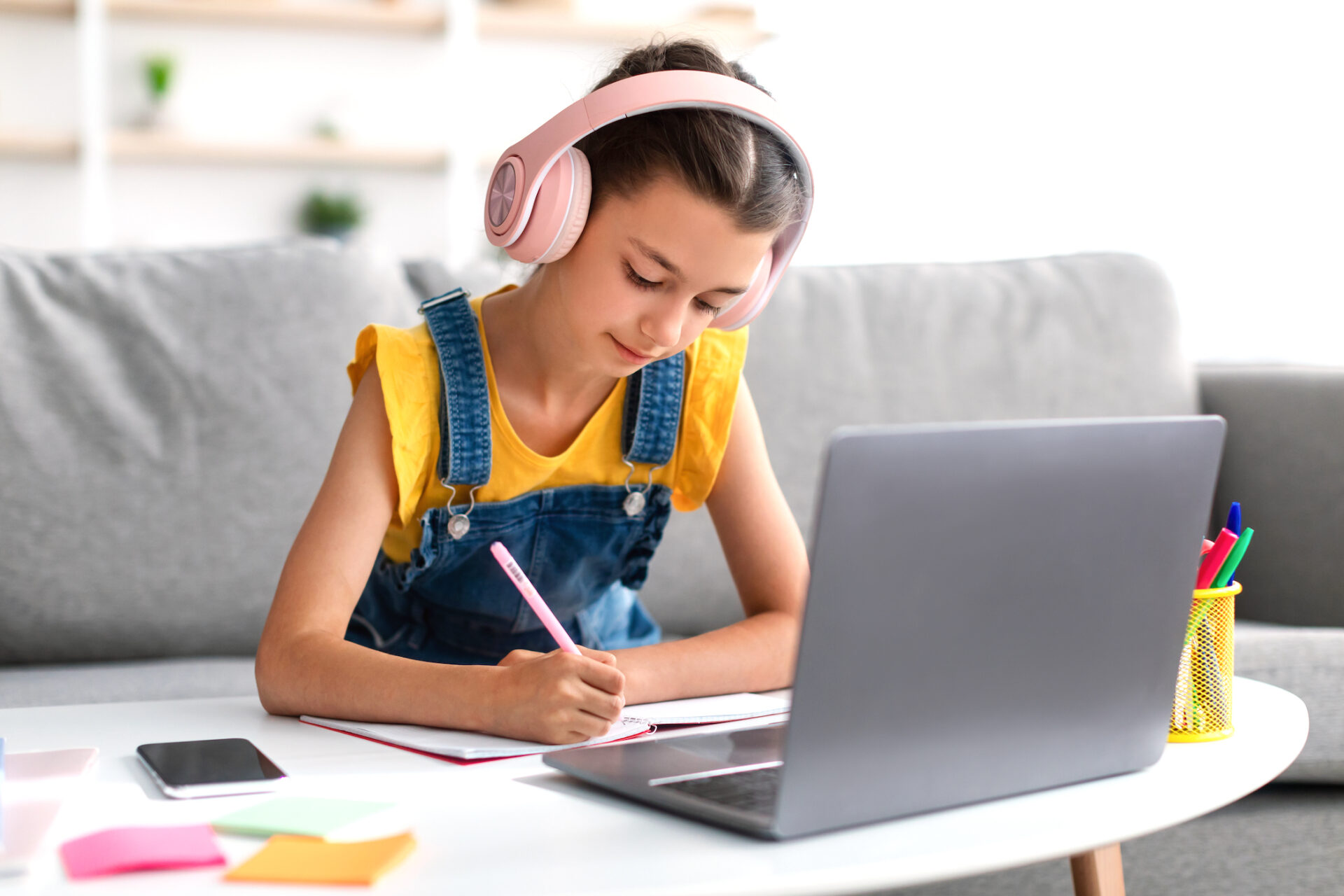 Schoolgirl in pink headset sitting at desk