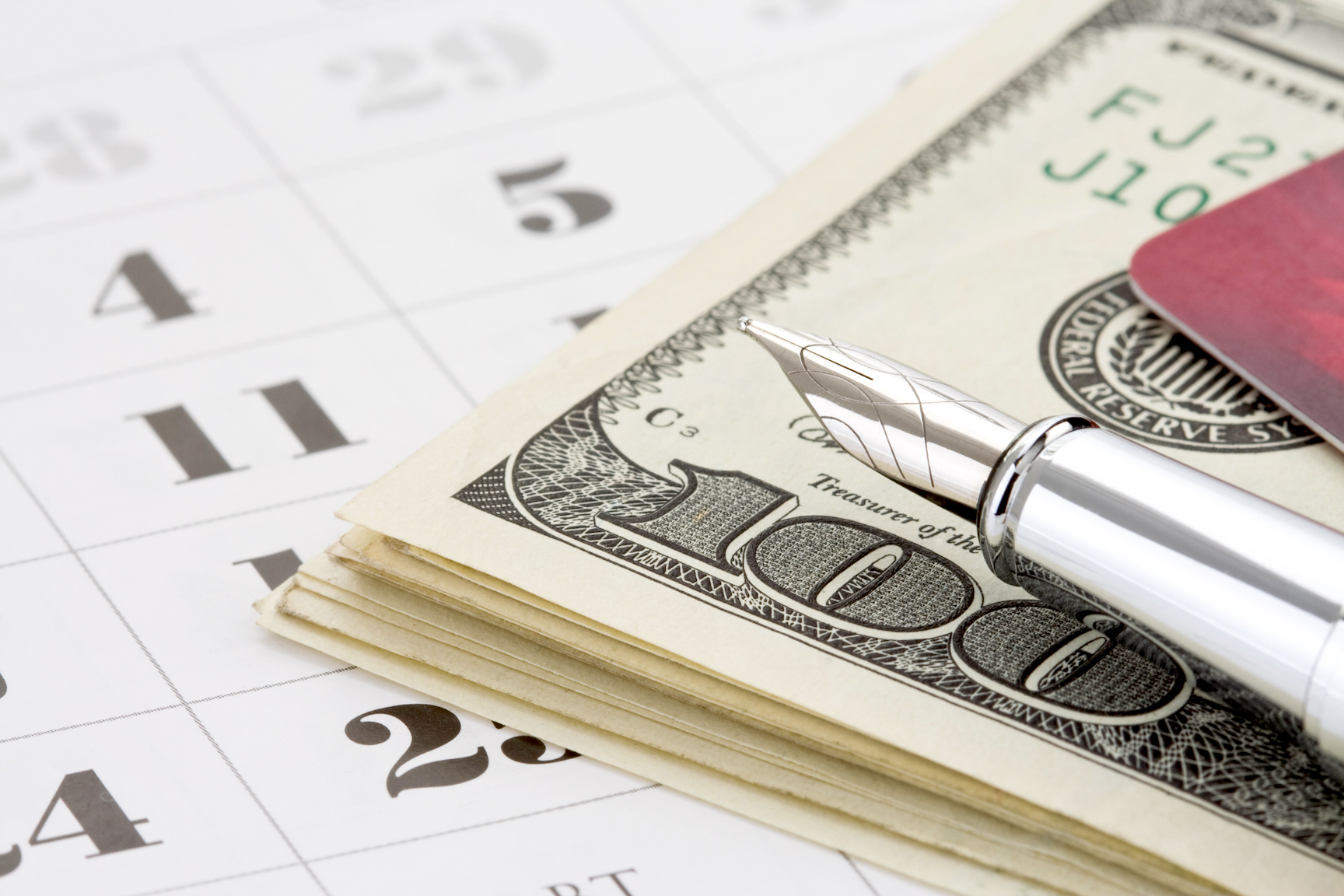 ink pen and dollar money on calendar background to symbolize the hidden costs of divorce litigation vs mediation